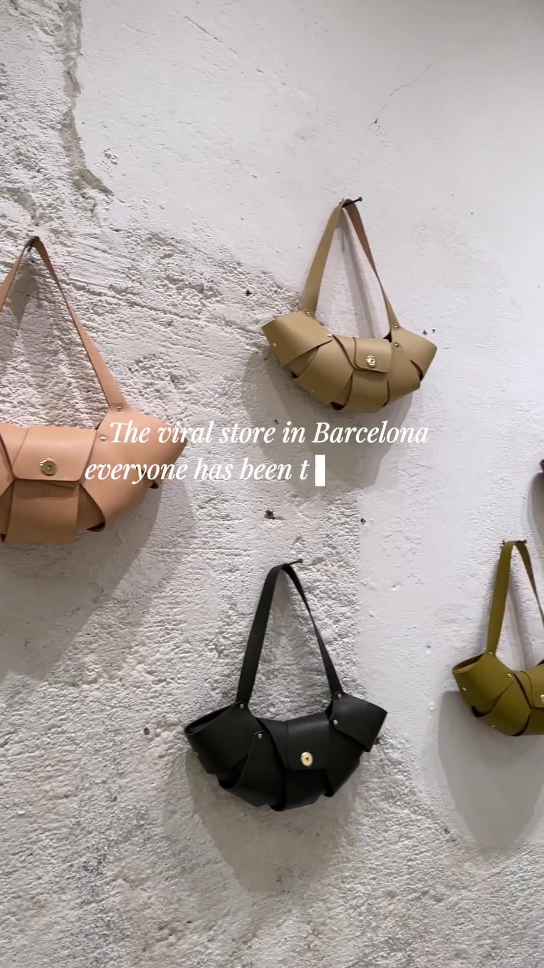 Leather handbags hanging on a white plaster wall in a Barcelona atelier